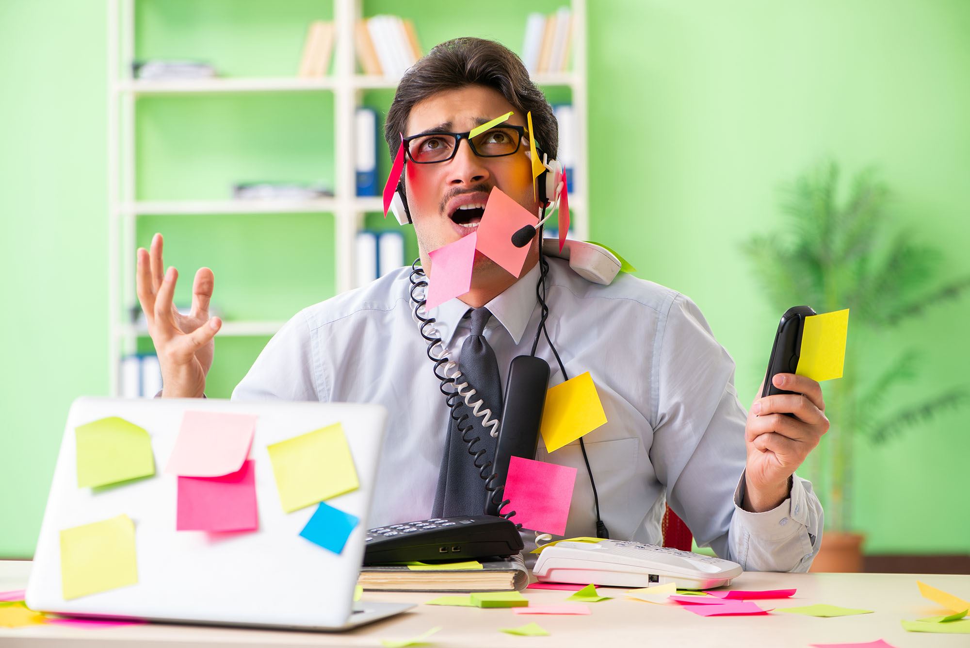 Man at IT service desk with post it notes and phones
